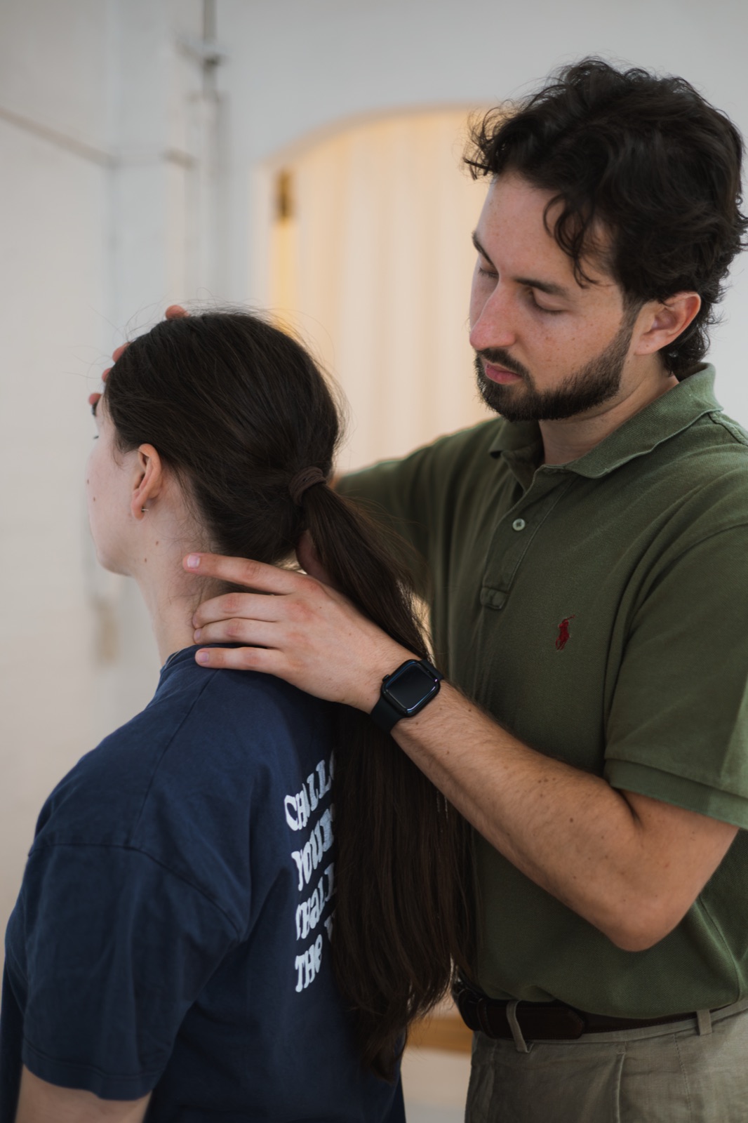 Tom feeling along the muscles at the base of a patient's neck