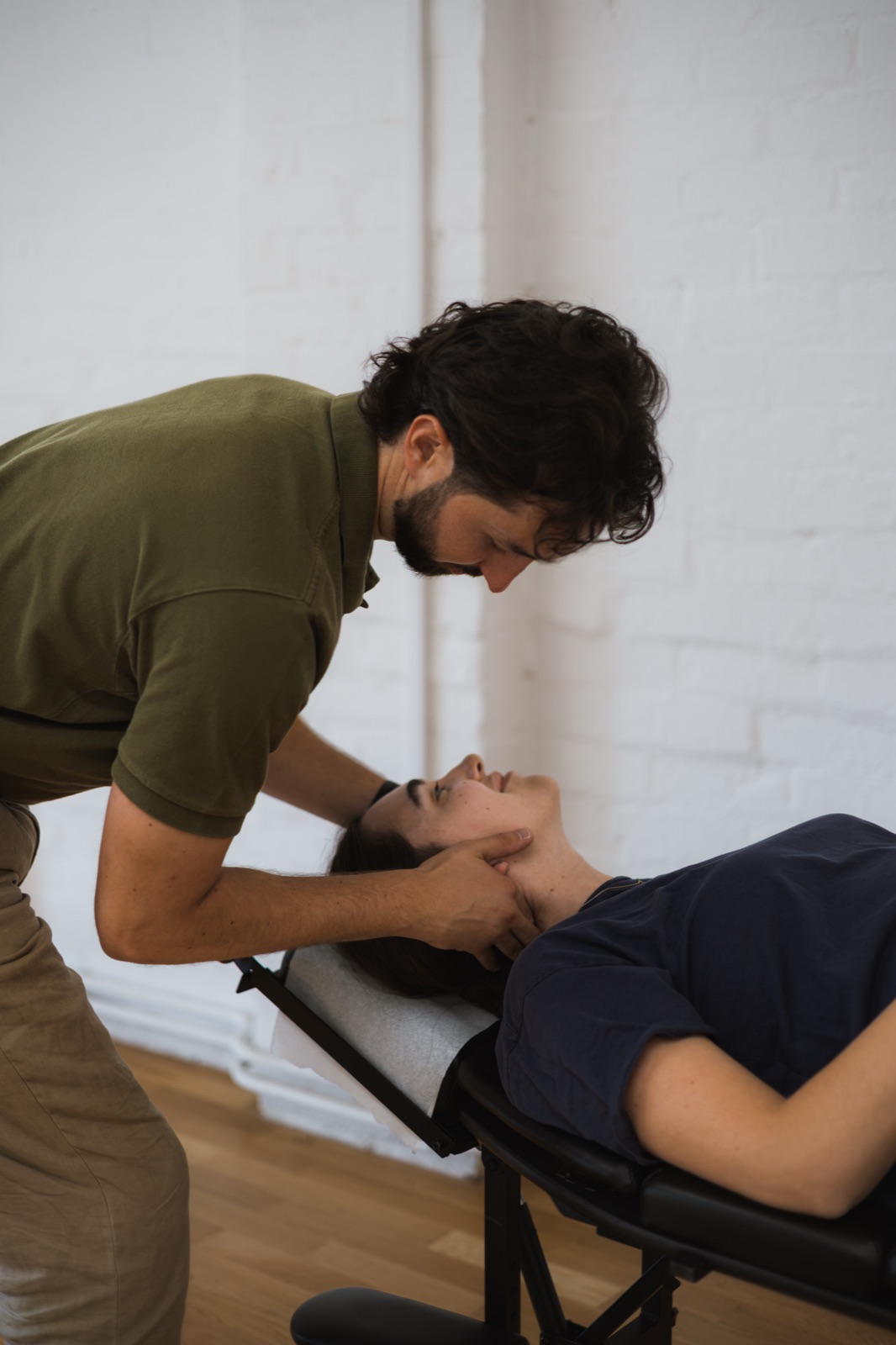 Tom treating a patient's neck as they lie on their back