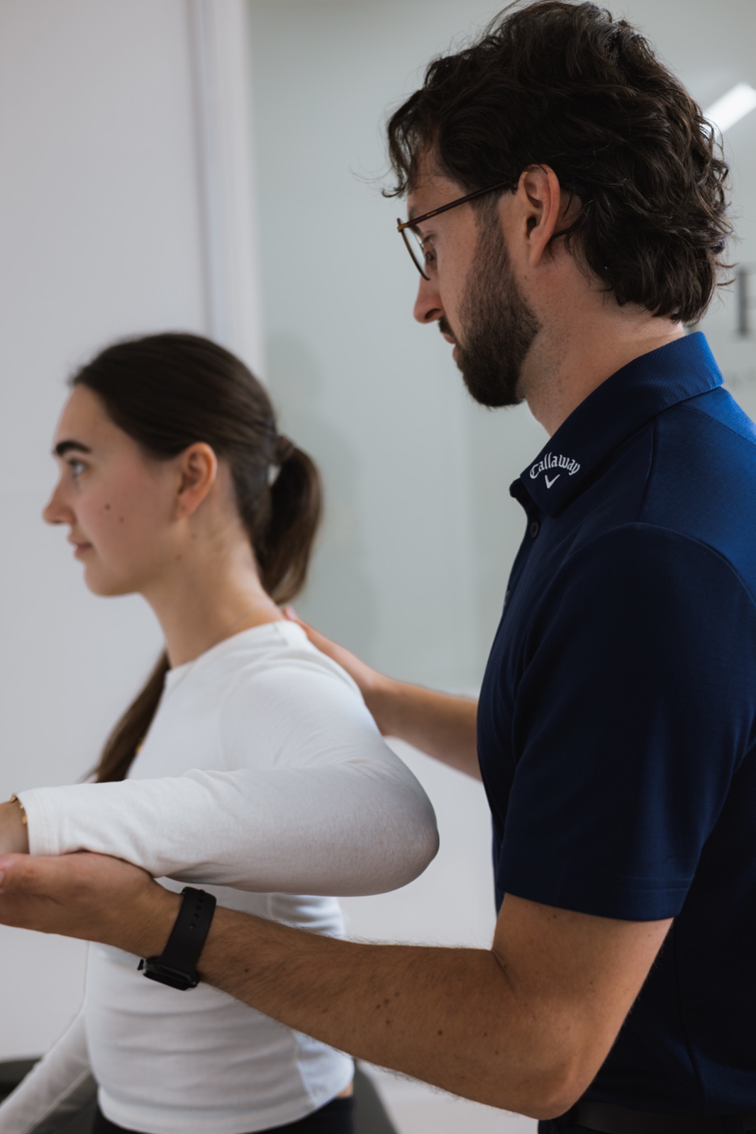Tom testing a patient's shoulder with the arm bent across the body